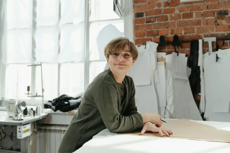 a young man sitting in a workshop next to a piece of paper