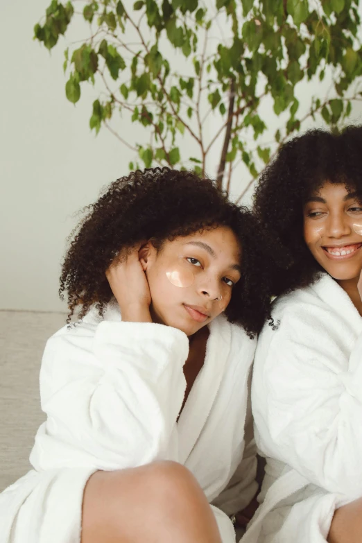 two women in towels on the bed and a tree