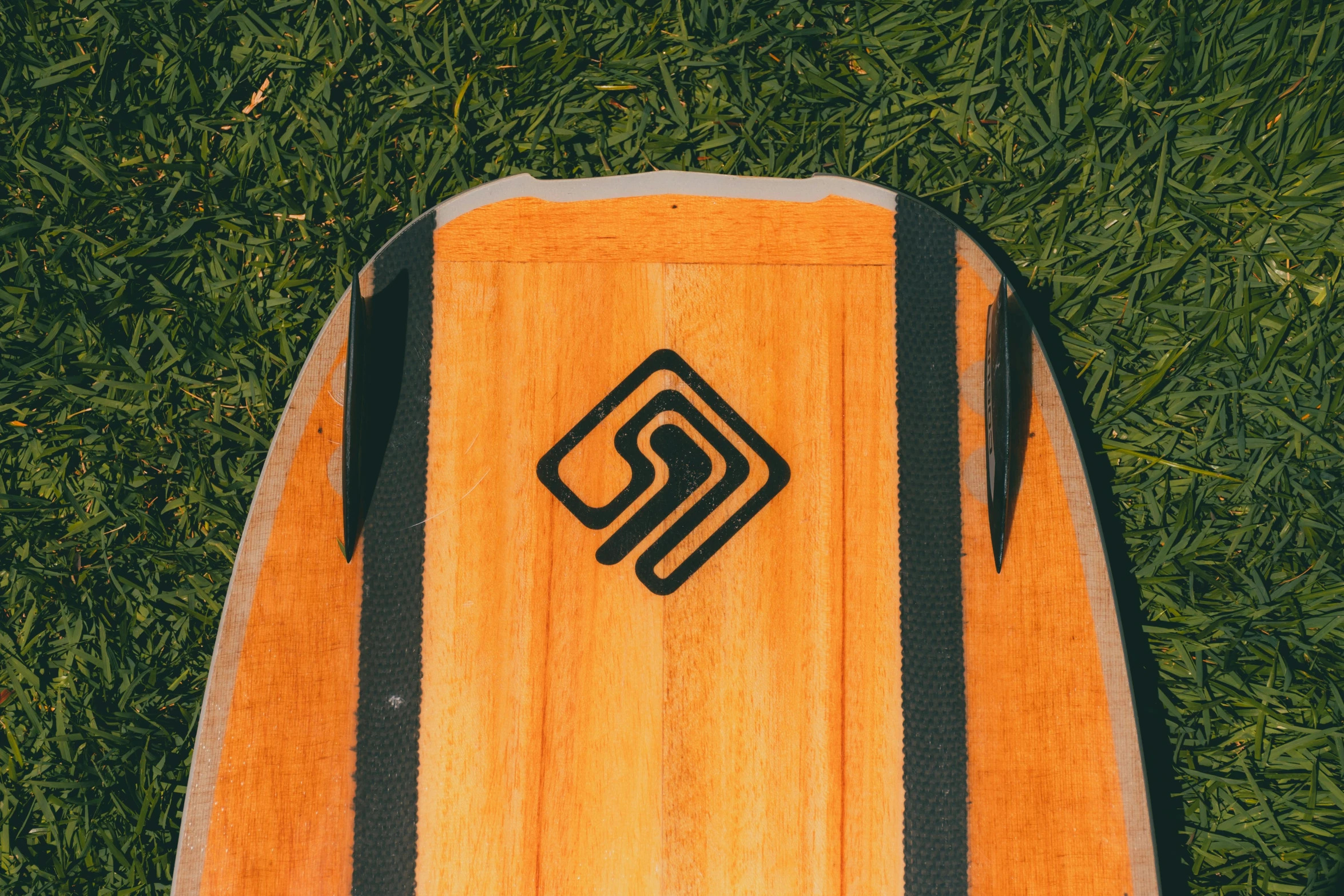 a surf board sitting in the grass near some green grass