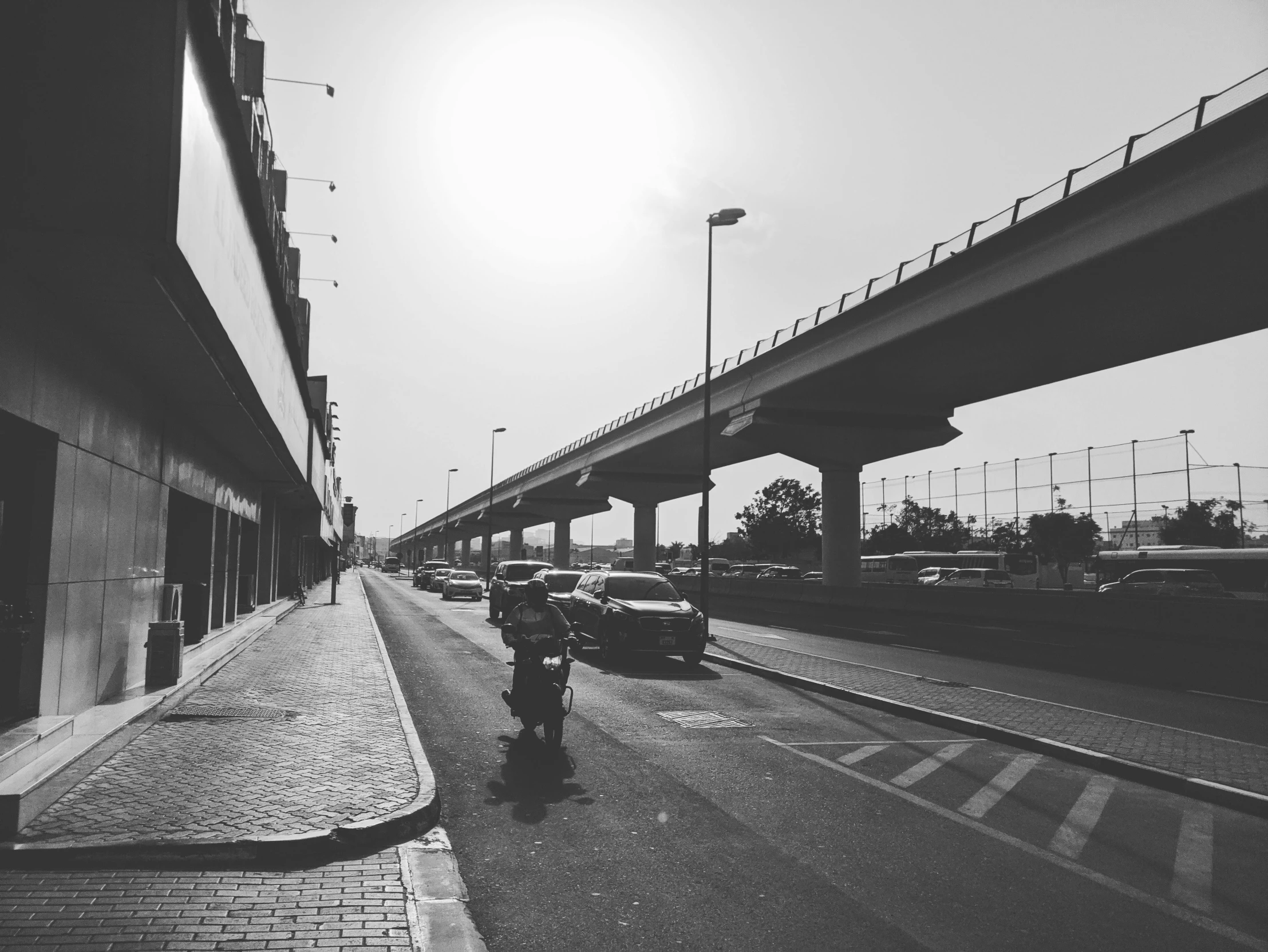 people are walking on the sidewalk under an overpass