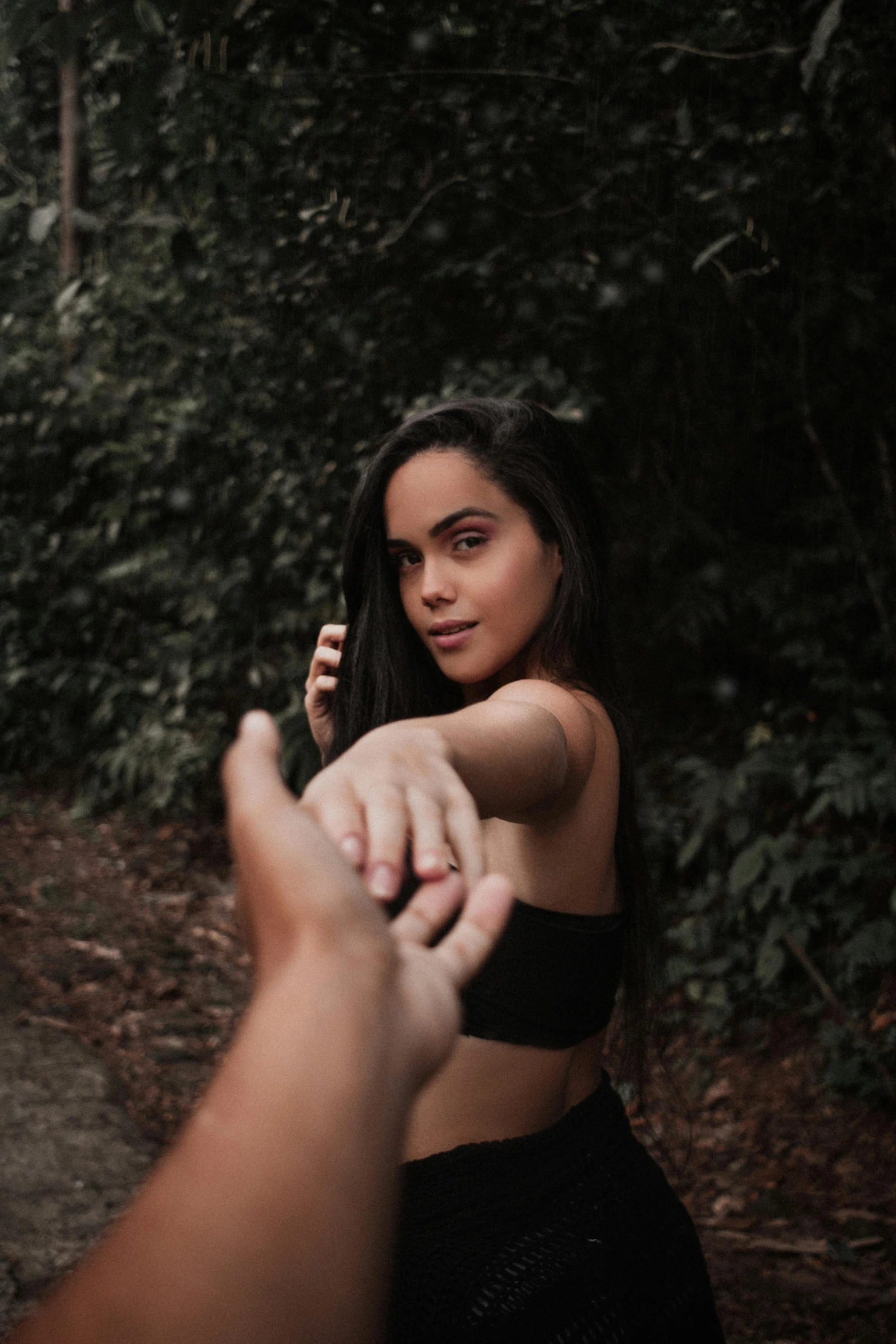 a beautiful woman in a black bikini standing in front of some trees