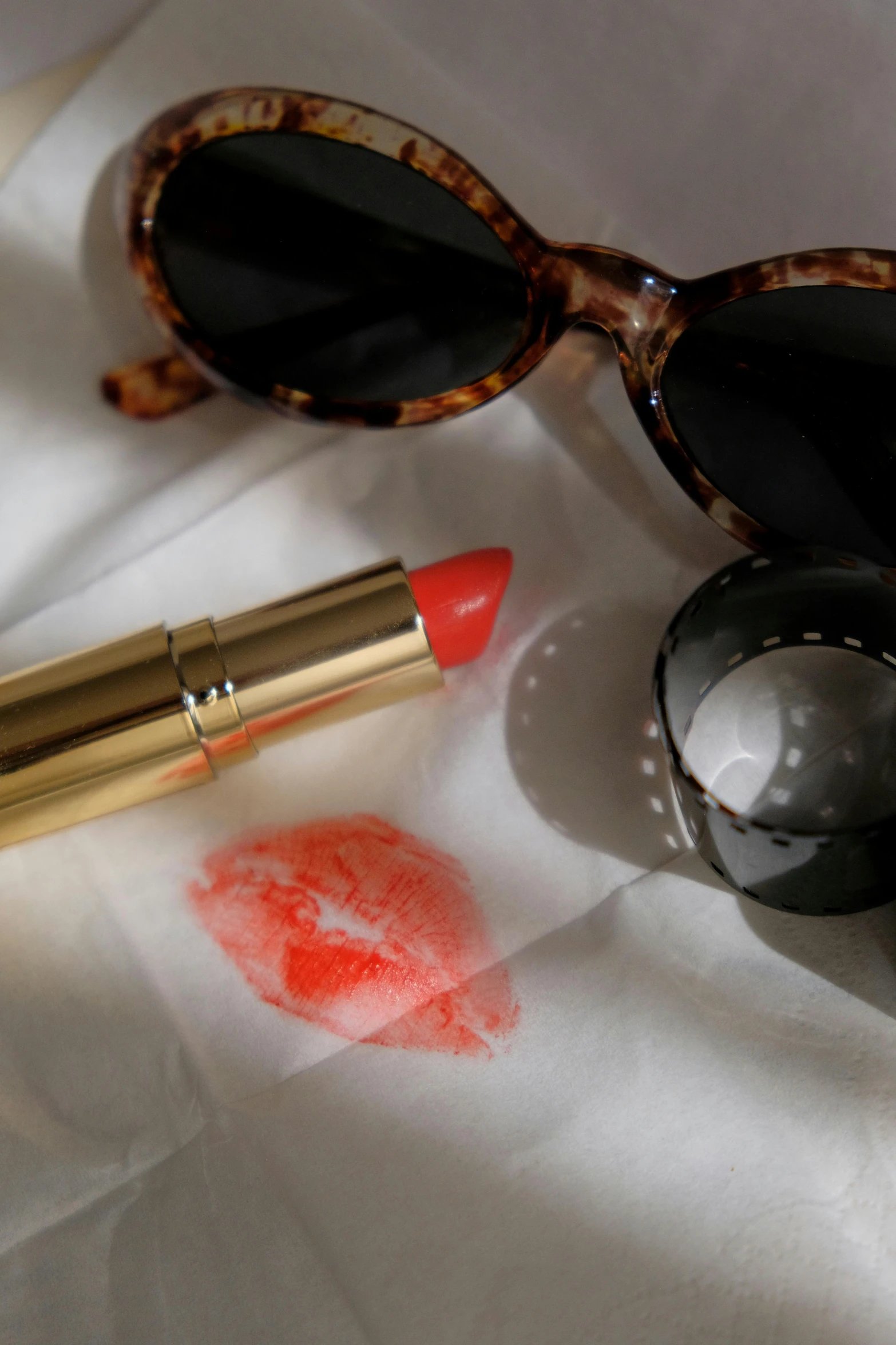 sunglasses, lipstick, and handprint on a bed