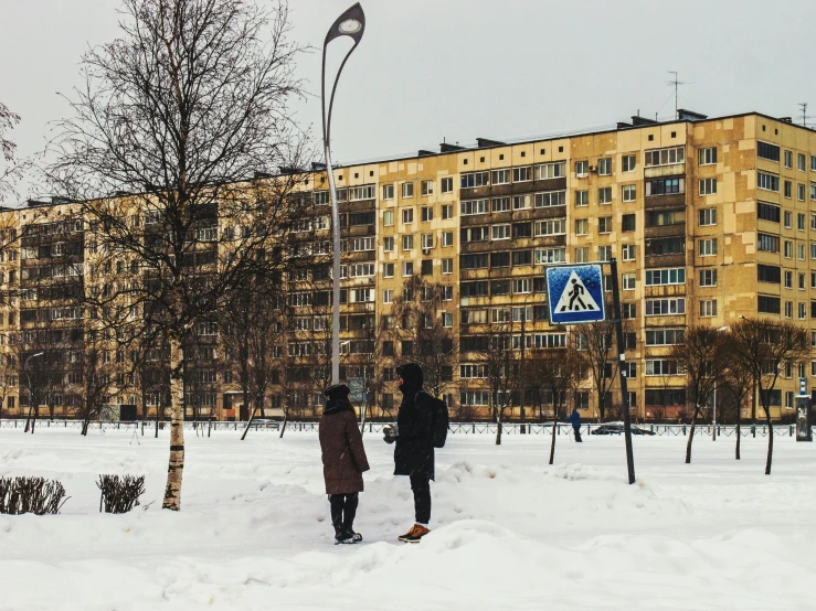 two people walking in the snow in front of a building