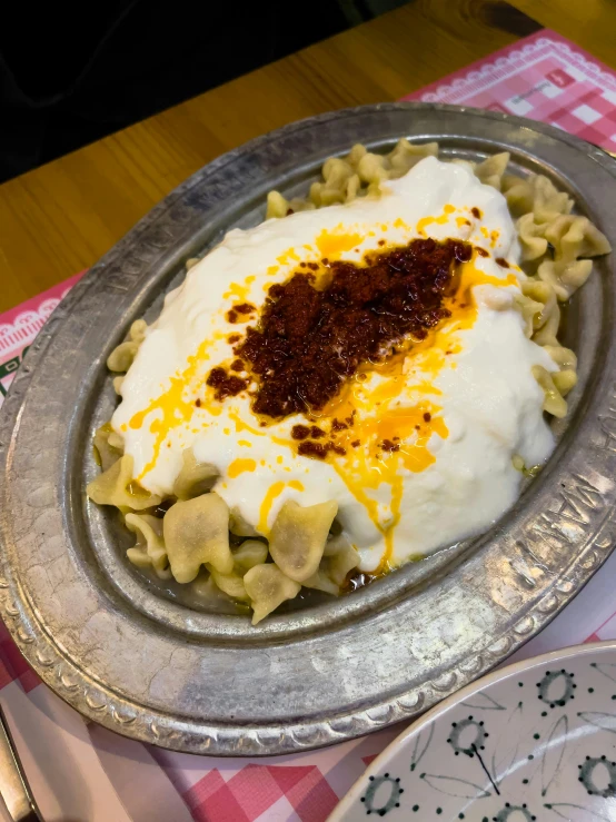 an oval dish has white sauce and some noodles