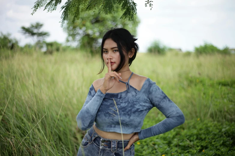 a woman standing in a grass field with her hands on her cheek