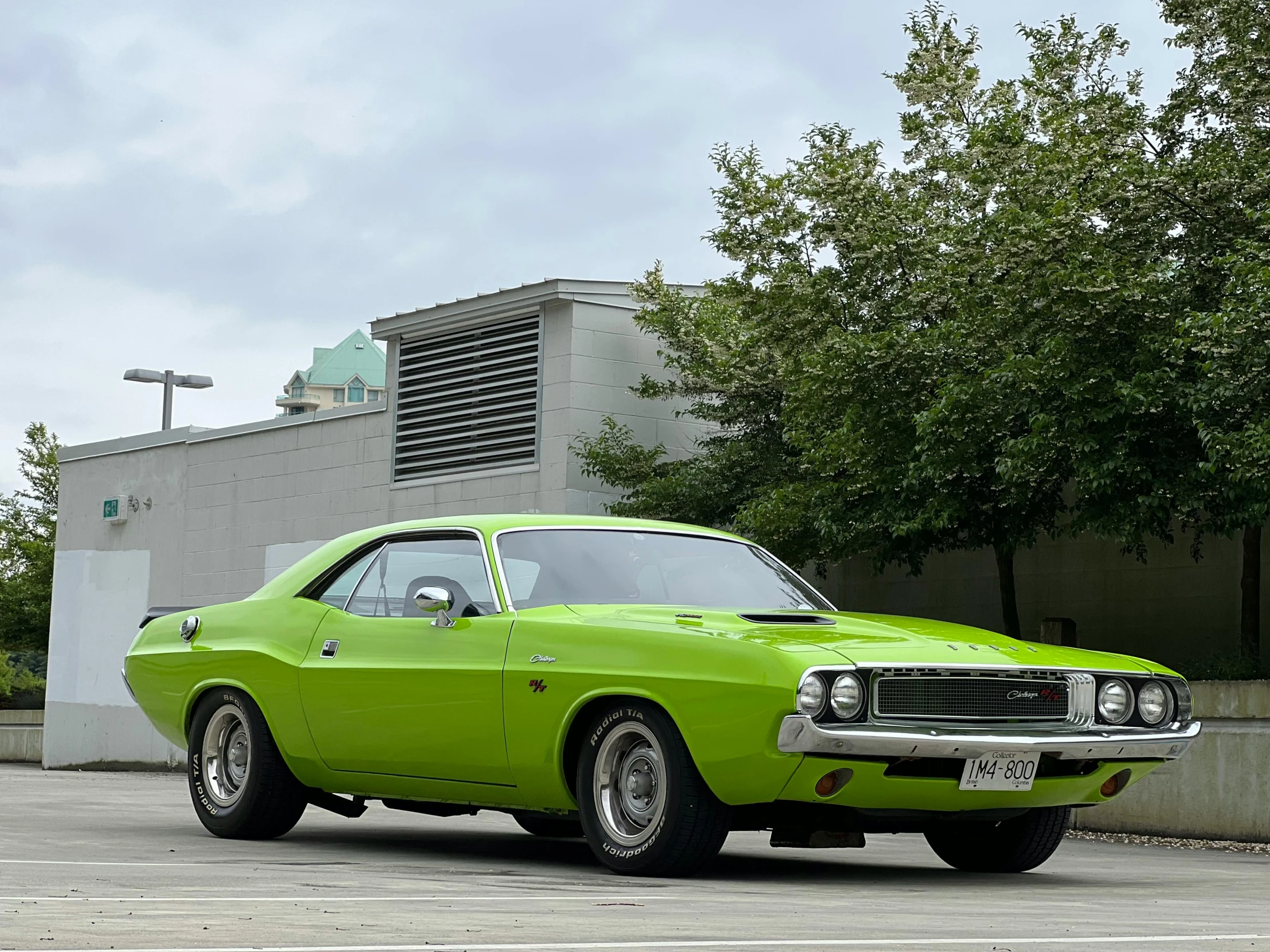 a green muscle car sitting in front of a building