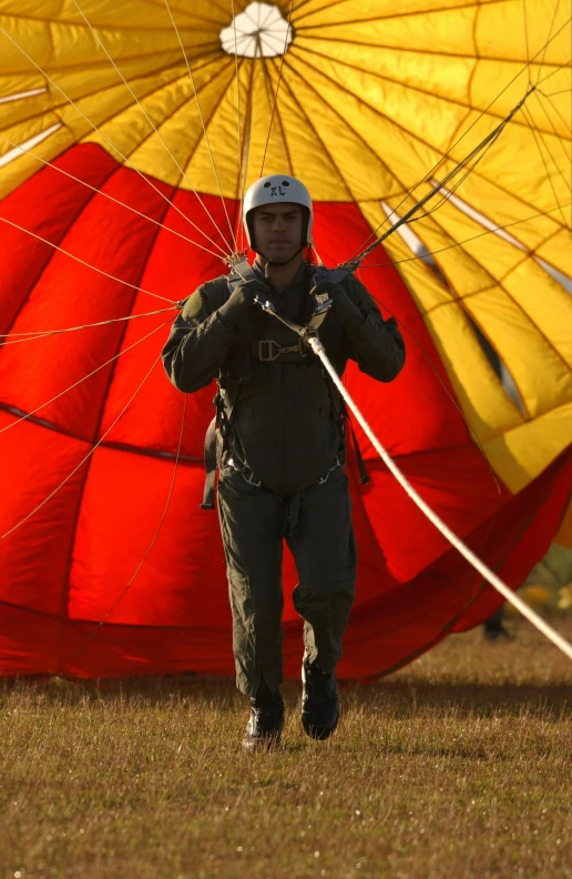 a man is holding the strings of his parachute while walking towards the ground