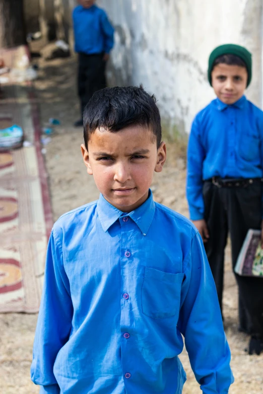 a group of boys in blue shirts and pants stand next to each other