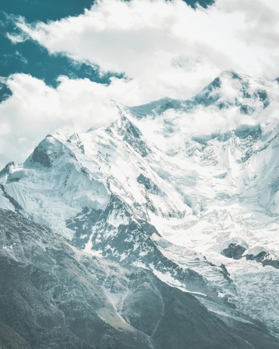 a mountain covered in snow with clouds on the top