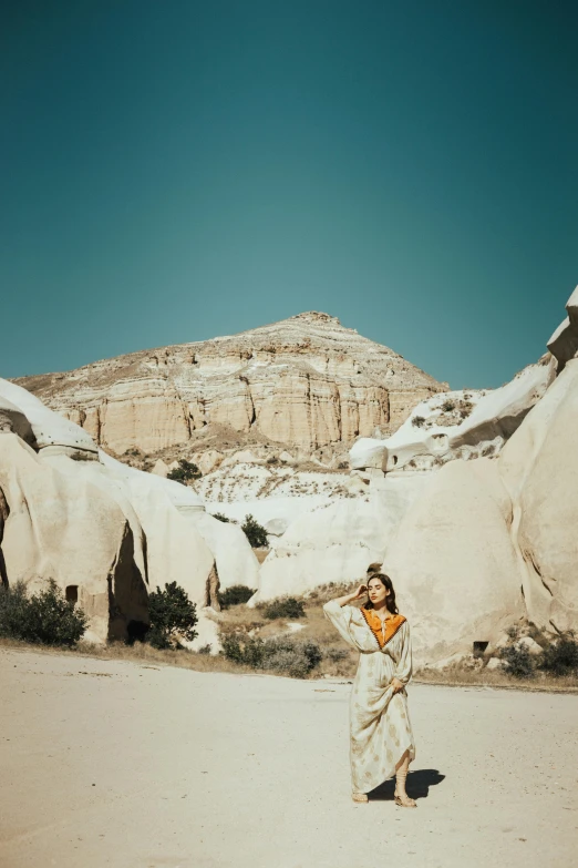 a  standing in a desert while wearing a dress