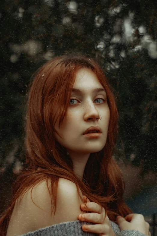 a woman with red hair standing in front of trees