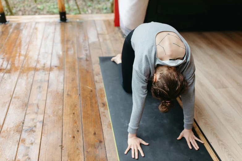 a young woman in a sports top practicing her yoga position on a black mat