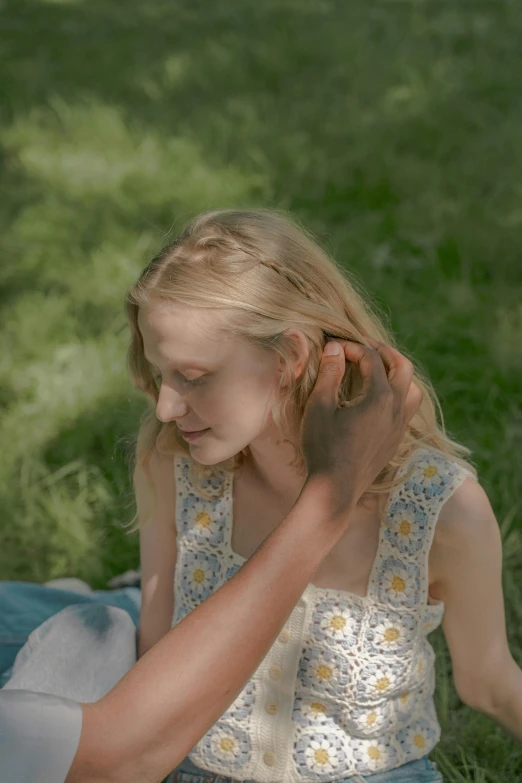 a young blonde girl wearing a white top sitting on the ground