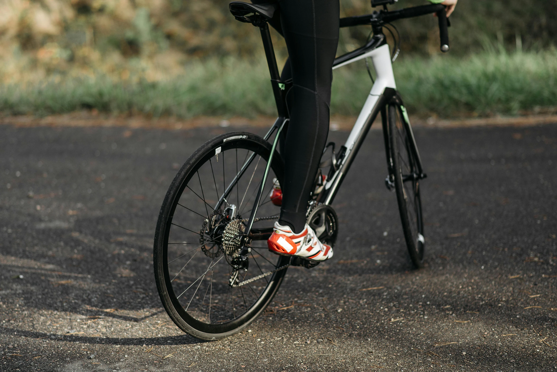 a person wearing black pants and black shoes riding a bicycle