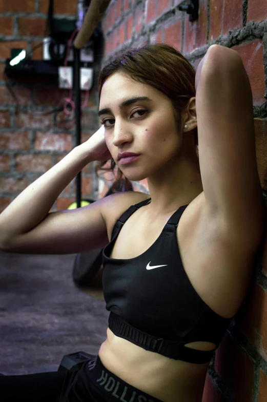 a woman leaning against a brick wall while holding her arm up