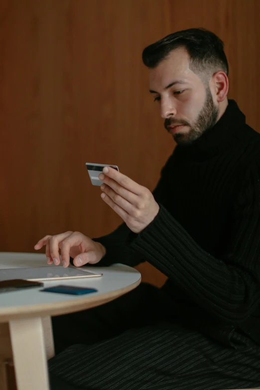 a man sitting at a table and looking at his cellphone