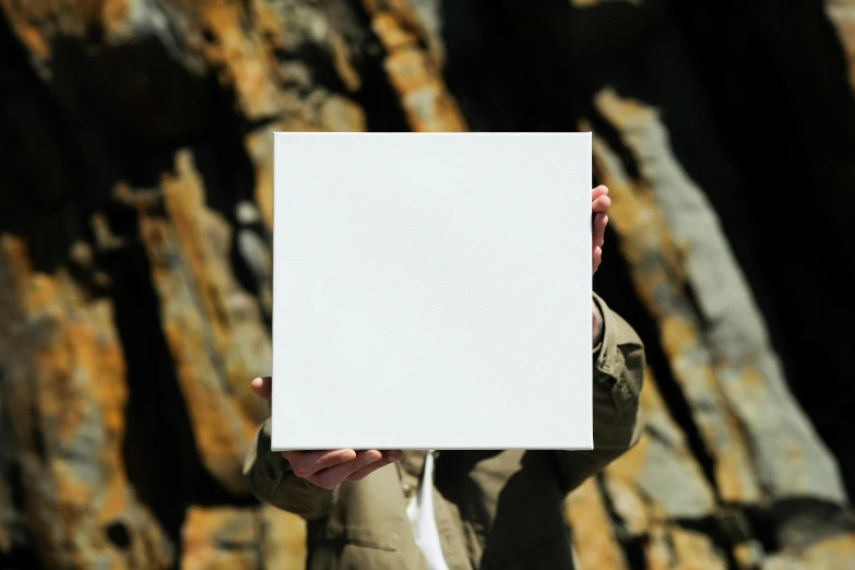 the person is holding up a blank paper in front of their face