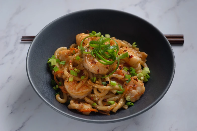 a bowl of stir fried noodles topped with shrimp