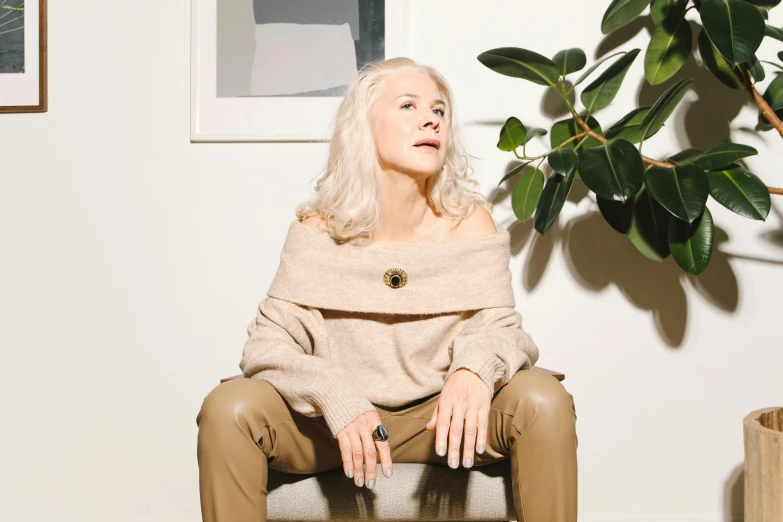 a woman is sitting on a chair next to a plant