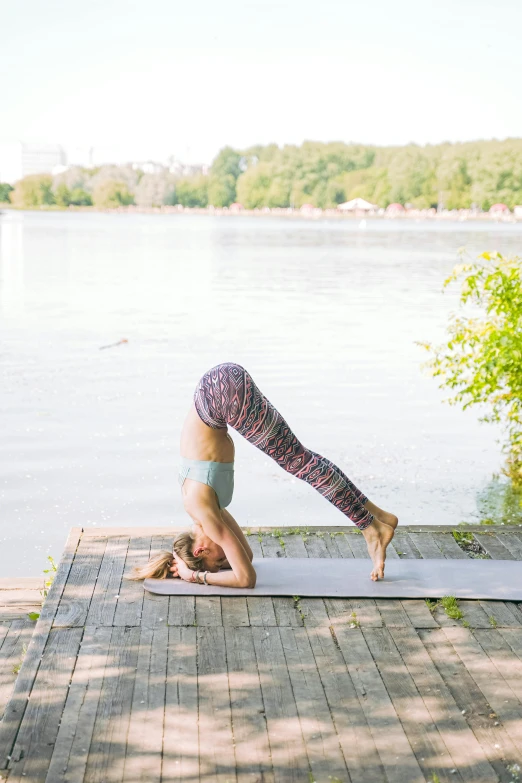 woman in yoga position on a board by the water