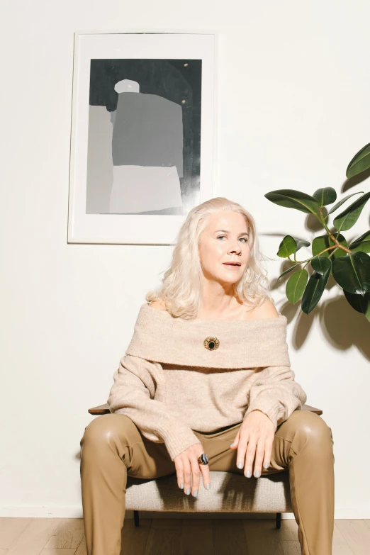 a woman sitting on a chair in front of a plant