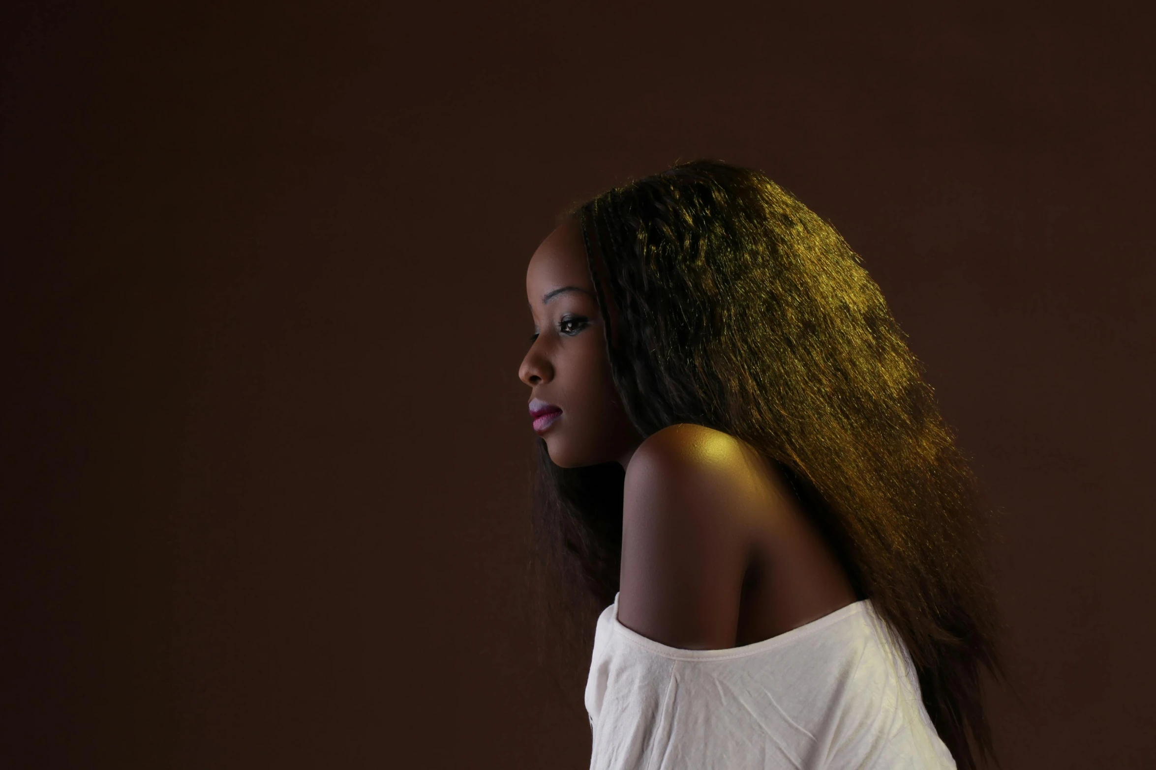 a woman wearing white stands in front of a brown background