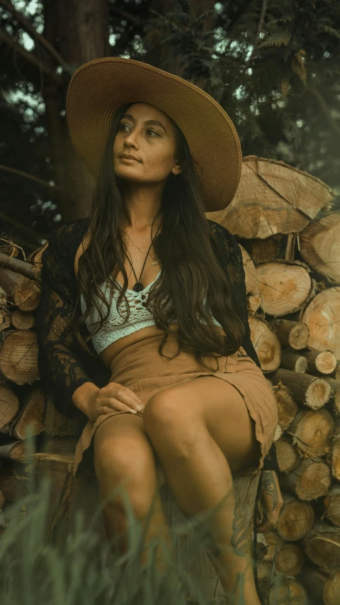 woman in straw hat posing in front of stacked logs