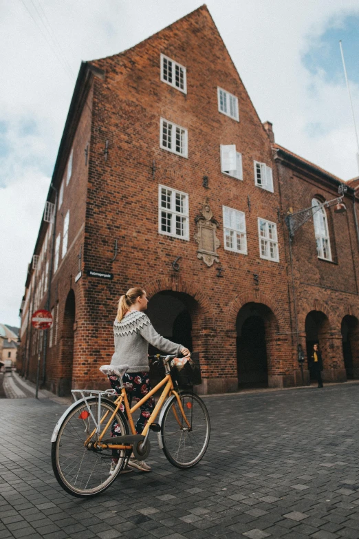 woman riding on back of bicycle next to a building