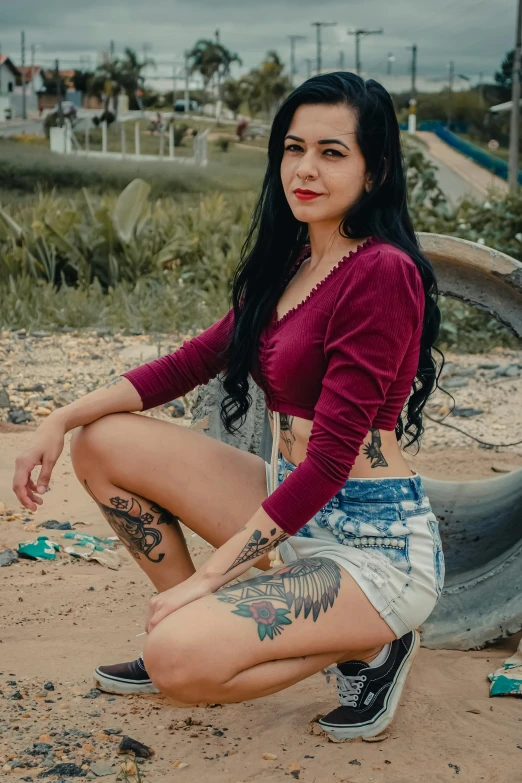 a young woman sitting in the dirt near a rock