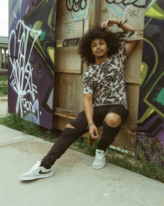 a young man sitting on a graffiti covered wall