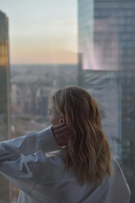 a woman with shoulder length curly hair looks out the window