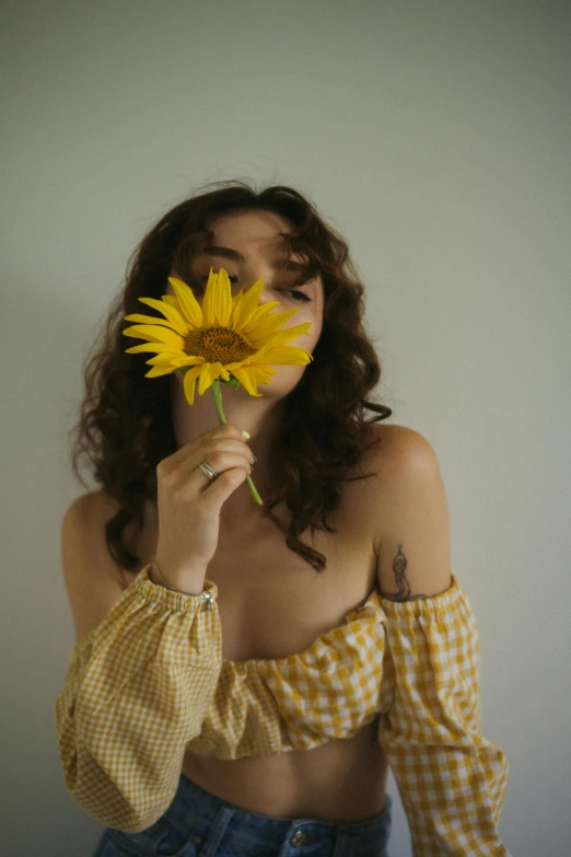 a woman holding up a yellow flower in her right hand