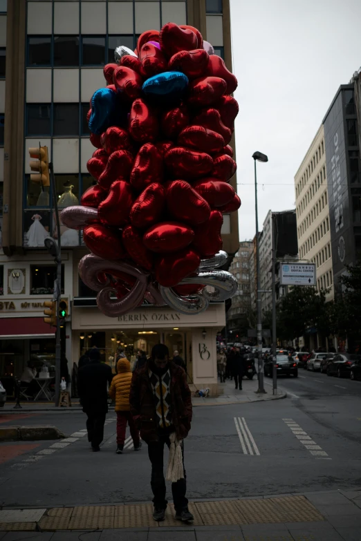 people walking on the street past a pile of balloons