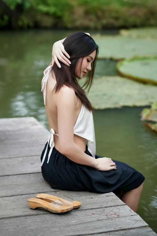 a beautiful young woman sitting on top of a dock