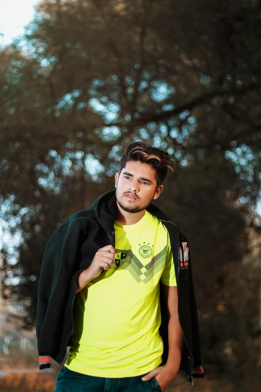 a man with a yellow shirt and black jacket posing for the camera