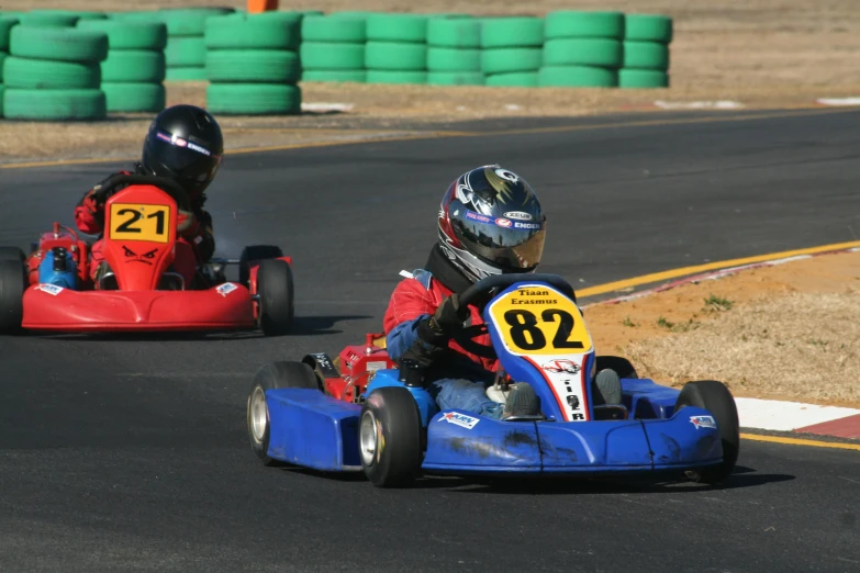 two small children are racing down a track in karts