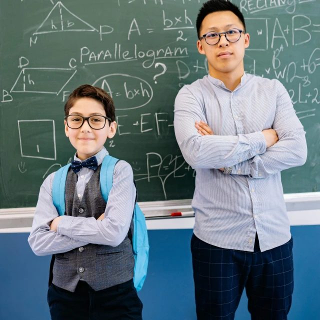 a man and a boy standing in front of a chalkboard