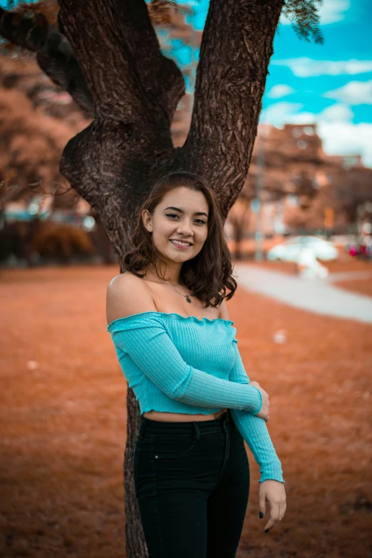 a woman standing by a tree posing for a po