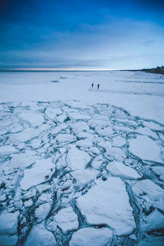 some ice and people walking along a large body of water