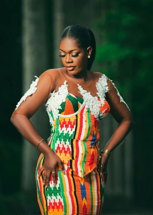 a woman with a colorful dress standing next to trees