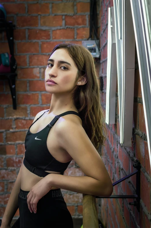 a beautiful young woman wearing a sports  in front of a brick wall