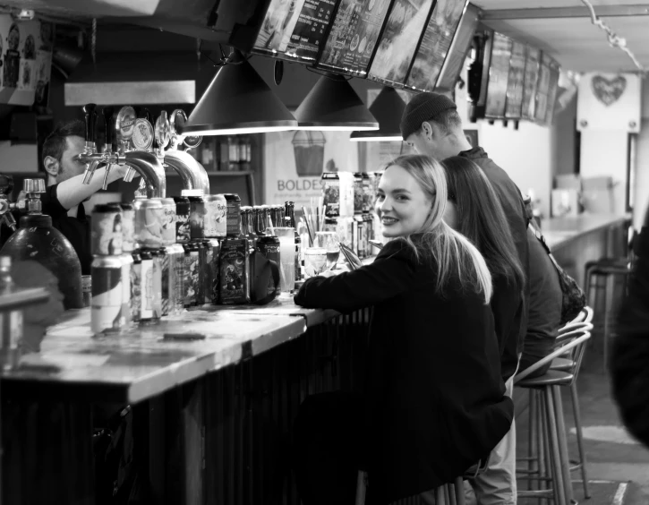 two women smiling at the bar while another looks on