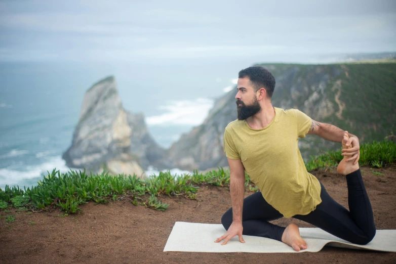 a man doing a yoga pose in front of the ocean