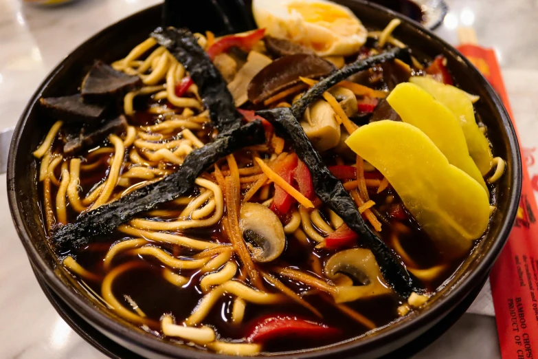 noodles in a bowl with vegetable slices and meats