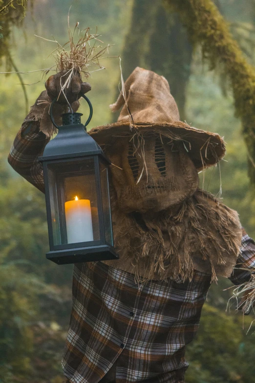 scarecrow holding lantern with lit candle inside