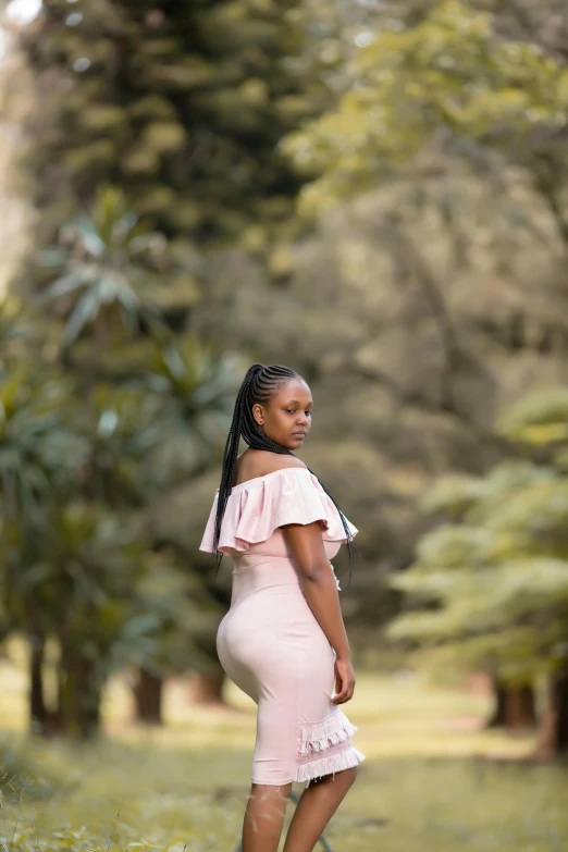 a pregnant black woman in pink dress posing for a pograph in the woods