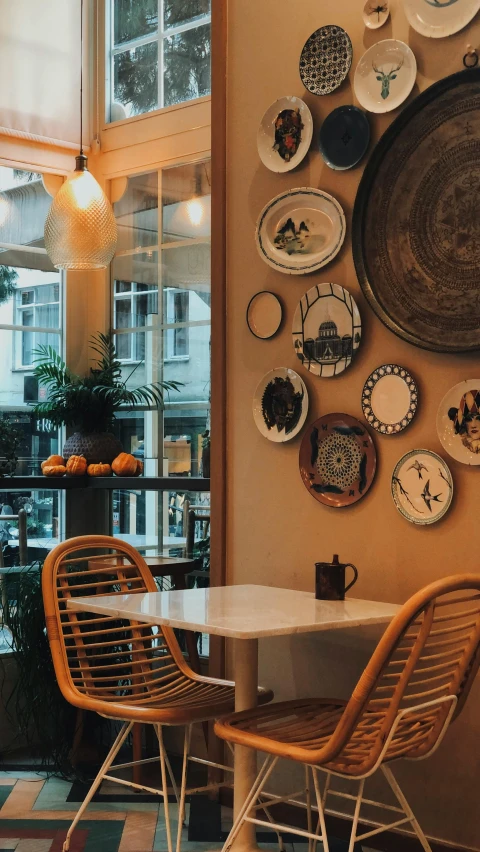 many plates hang on a wall near a dining table