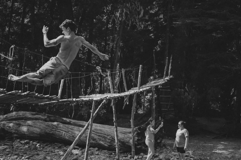 a man jumps over a log while another man watches