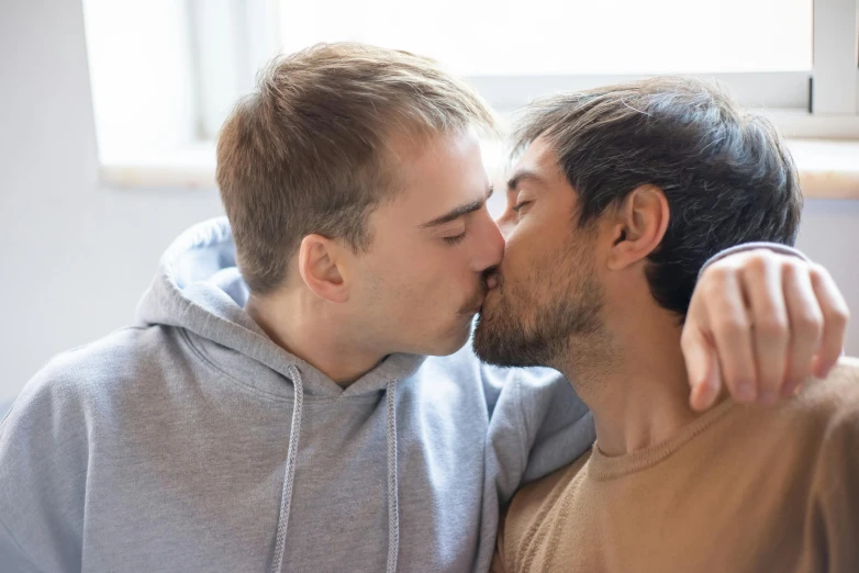 a couple kissing and making faces while wearing sweatshirts