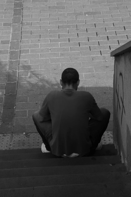 man sitting on steps next to small brick building